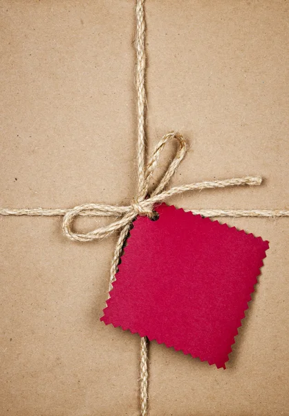 Подарок с красной биркой в коричневой бумаге — стоковое фото