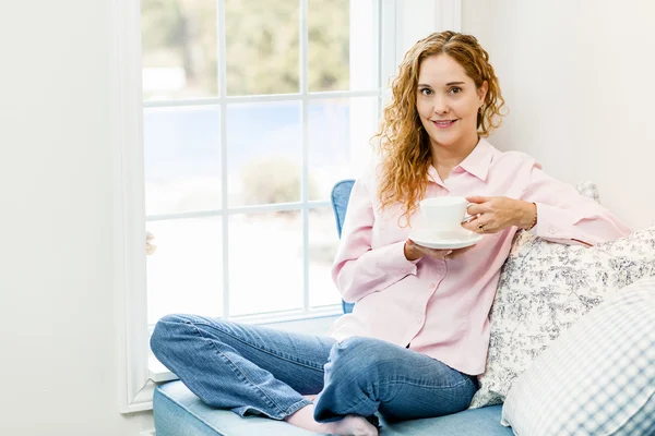 Woman relaxing by the window with beverage — Stock Photo, Image