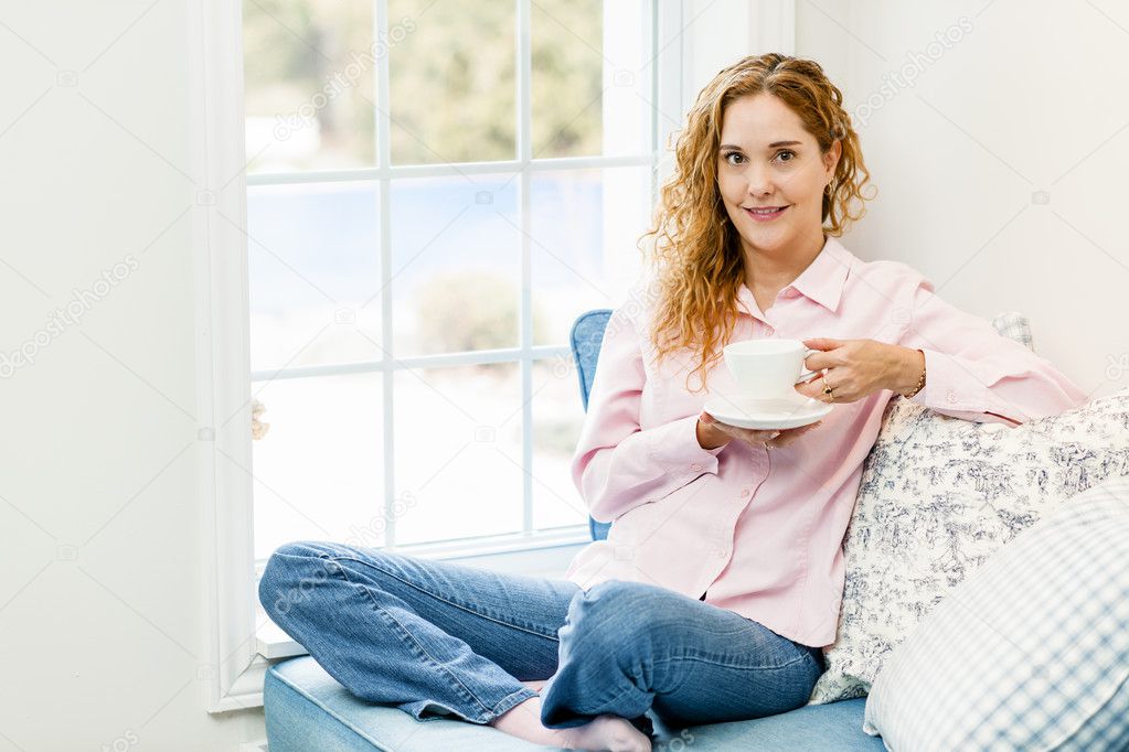 Woman relaxing by the window with beverage