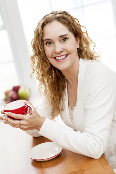 Mujer sonriente sosteniendo taza de café rojo —  Fotos de Stock