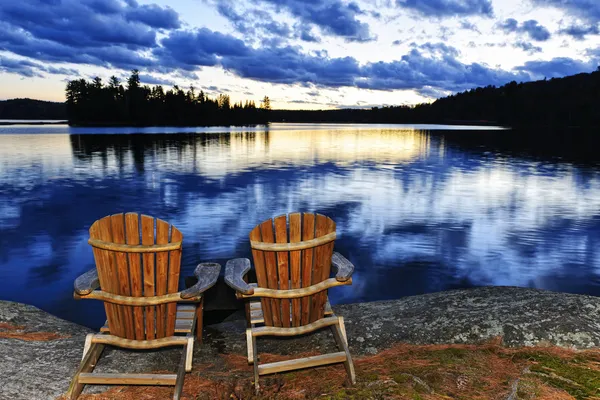 Sedie in legno al tramonto sulla riva del lago — Foto Stock