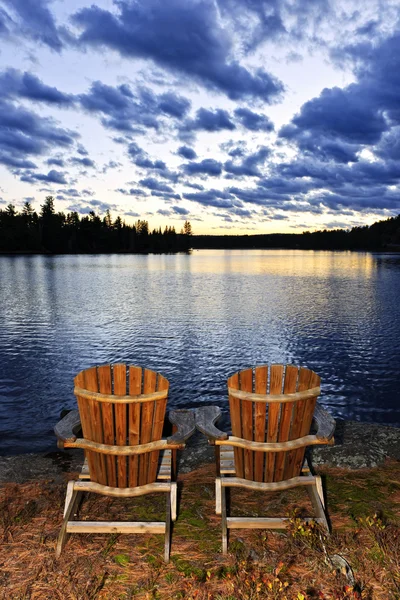 Holzstühle bei Sonnenuntergang am Seeufer — Stockfoto