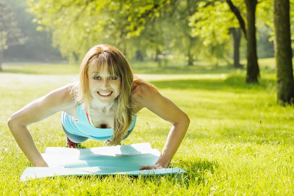 Woman doing pushups in morning park — Stock Photo, Image