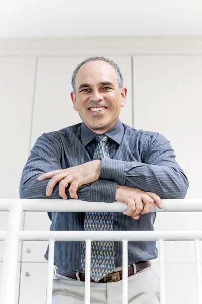 Businessman standing in office hallway smiling — Stock Photo, Image