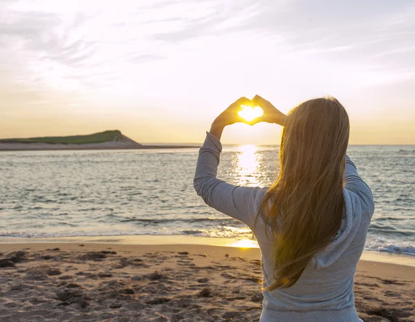 Flicka håller hand i hjärtat form på stranden — Stockfoto