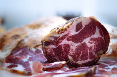 Close up of an artisanal Calabrian capocollo sliced on a cutting board clipart