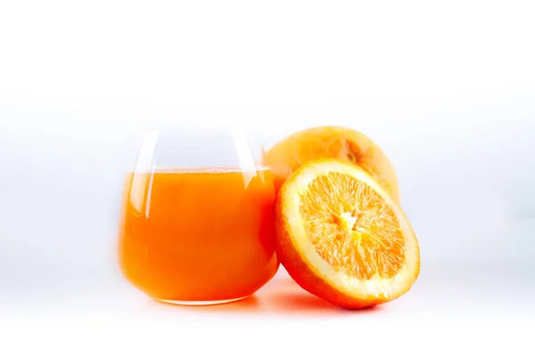 一杯新鲜榨橙汁和两个橙子 其中一个被切成两半 — 图库照片#