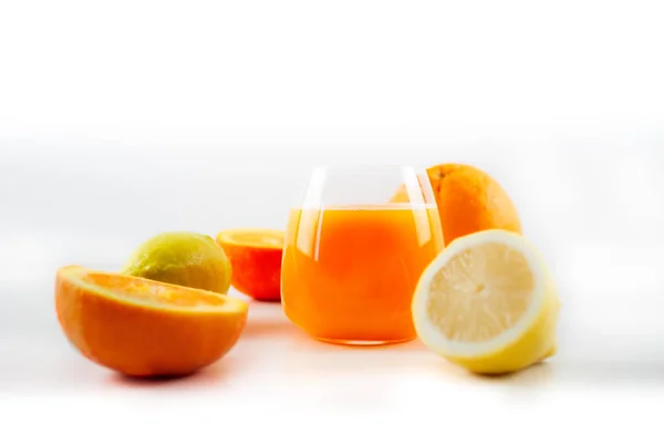 一杯新鲜榨橙汁和柠檬汁加冰块 在模糊的白色背景上切碎柠檬和橙子 — 图库照片#