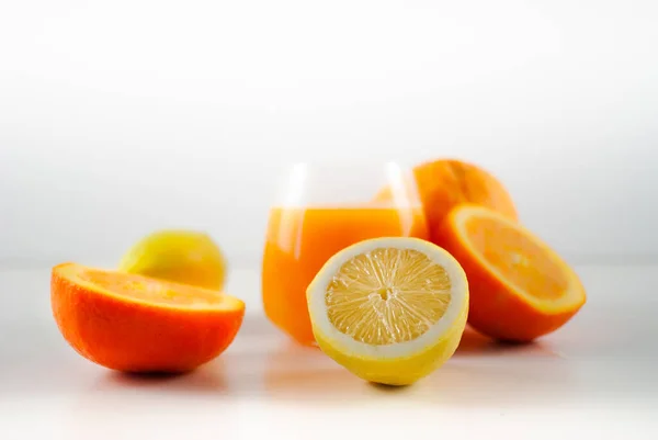 柠檬在前景与橙子和玻璃杯橙汁为背景 — 图库照片#