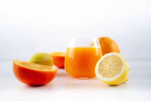 一杯新鲜榨橙汁 背景中夹着橙子和柠檬 前景中夹着一片柠檬 — 图库照片#