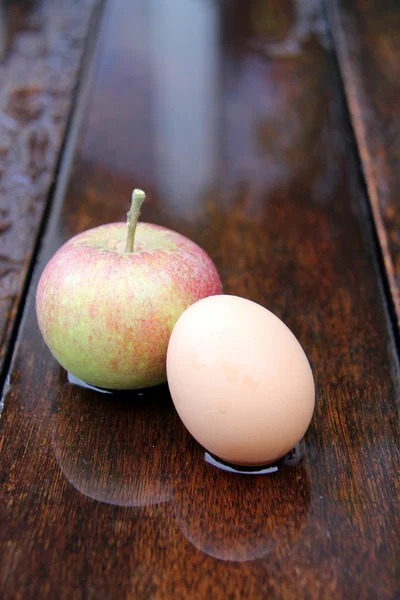 Huevo y manzana sobre madera — Foto de Stock