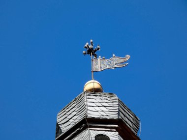 Rüzgâr yönündeki sığırcıklar, Evanjelik Kilisesi 'nin mavi gökyüzünün altında kaybolduğunu gösteriyor.  