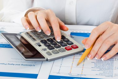 kalem ve presleme hesap makinesi düğmelerinin belgeler üzerinde tutan eller