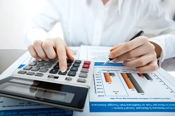 kalem ve presleme hesap makinesi düğmelerinin belgeler üzerinde tutan eller