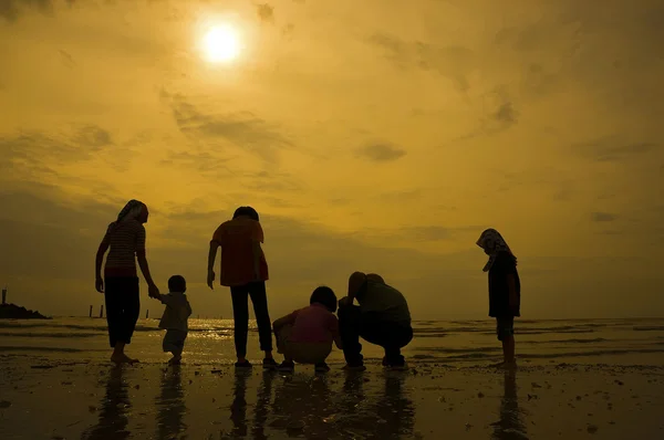 Grupo silhueta de crianças brincando na praia — Fotografia de Stock