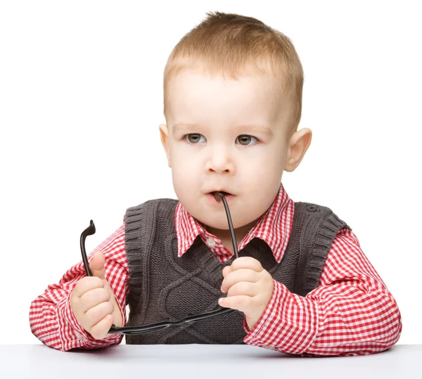 Cute little child is biting glasses — Stock Photo, Image