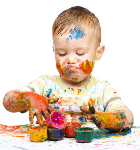 Мальчик играет с красками.
