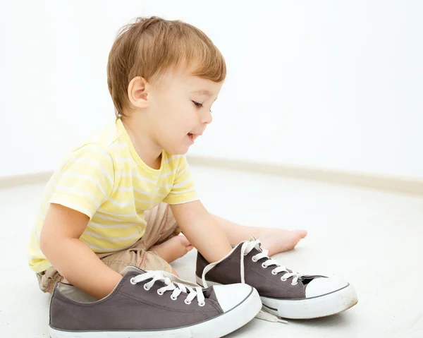Хлопчик грає з великим кросівки — стокове фото