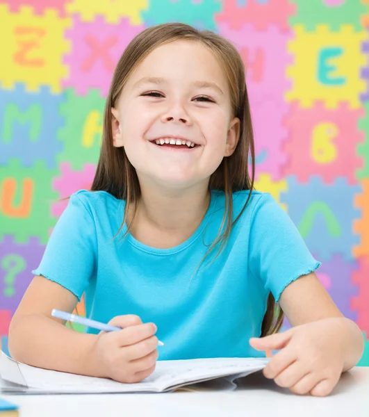 Little girl is writing using a pen — Stock Photo, Image