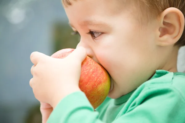 Niño pequeño muerde manzana roja y sonríe —  Fotos de Stock