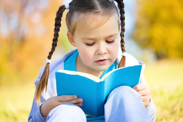 Roztomilá holčička čte knihu — Stock fotografie