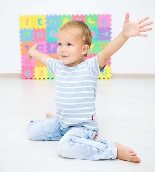 Little boy raised his hands while sitting on floor — Stock Photo, Image