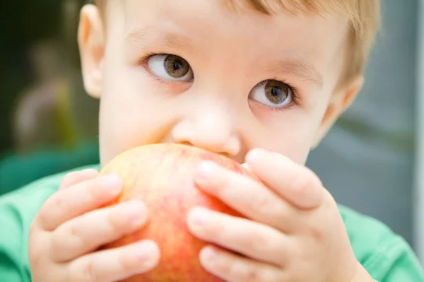 Litet barn är bita rött äpple — Stockfoto
