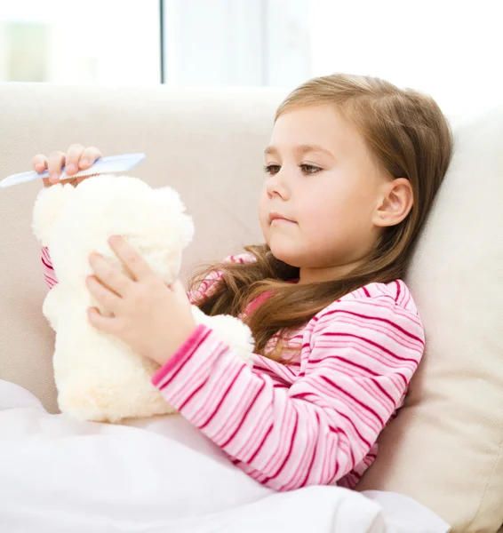 Kleines Mädchen kämmt ihren Teddybär — Stockfoto