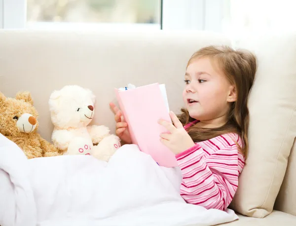 Petite fille lit un livre pour ses ours en peluche — Photo