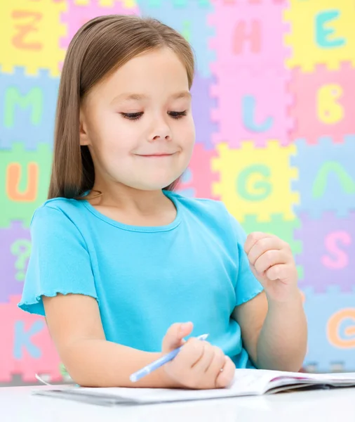 La niña está escribiendo usando un bolígrafo —  Fotos de Stock