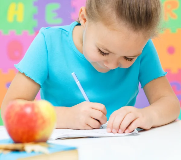 Little girl is writing using a pen — Stock Photo, Image