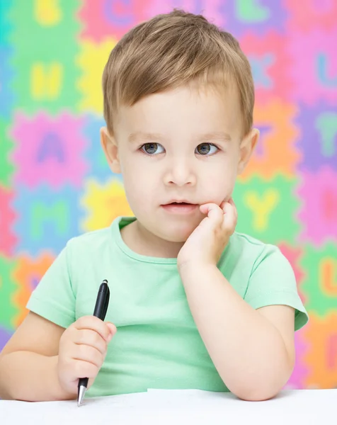 小さな男の子は彼のコピーブックに書いています。 — ストック写真