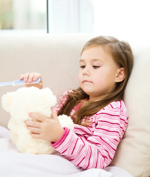 Kleines Mädchen putzt ihren Teddybär — Stockfoto