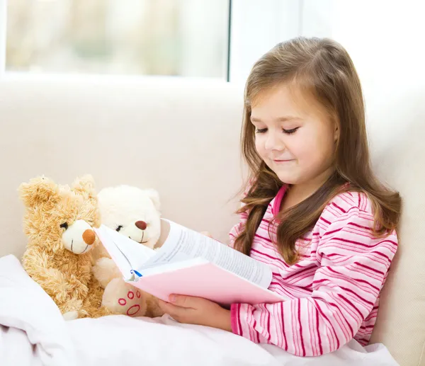Маленькая девочка читает сказку для своих плюшевых мишек — стоковое фото