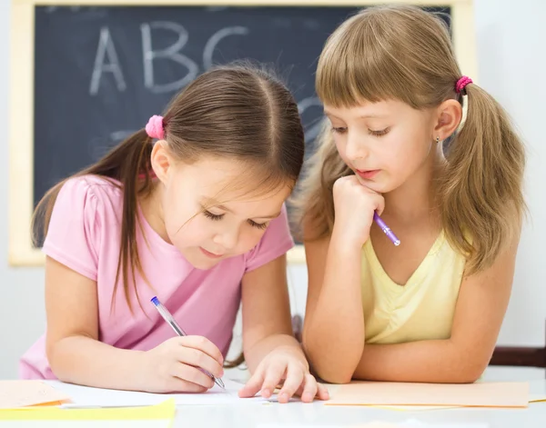 Little girl is writing using a pen — Stock Photo, Image