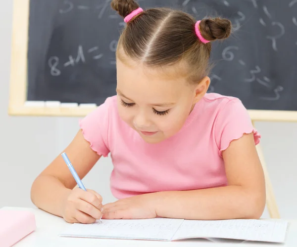 La niña está escribiendo usando un bolígrafo —  Fotos de Stock