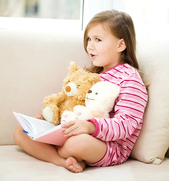 Klein meisje is het lezen van een verhaal voor haar teddy bears — Stockfoto