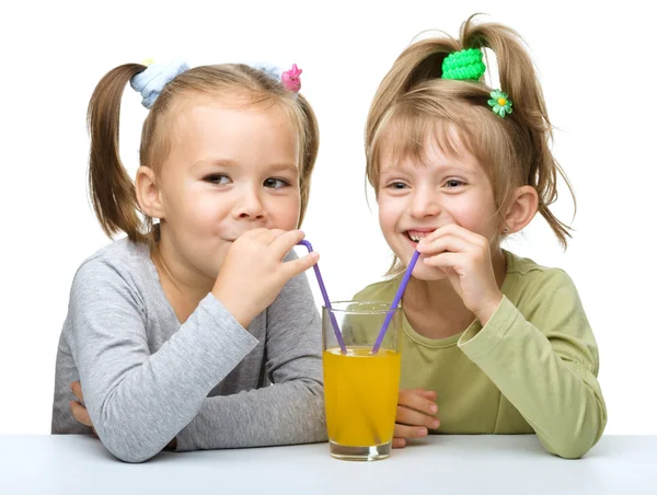 Zwei kleine Mädchen trinken Orangensaft — Stockfoto