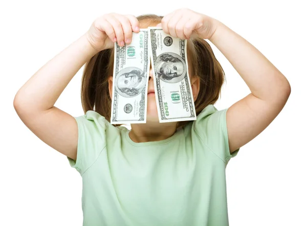 Little girl is covering her eyes with dollars — Stock Photo, Image