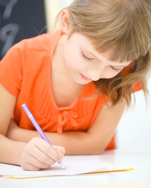 La niña está escribiendo usando un bolígrafo Imagen De Stock