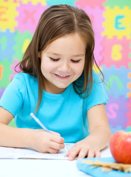 La niña está escribiendo usando un bolígrafo — Foto de Stock