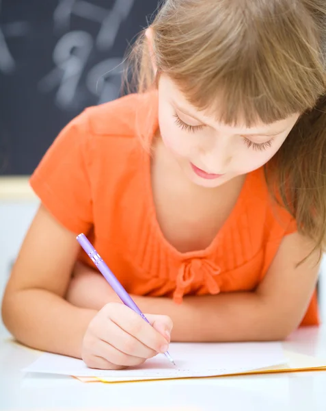 La niña está escribiendo usando un bolígrafo — Foto de Stock