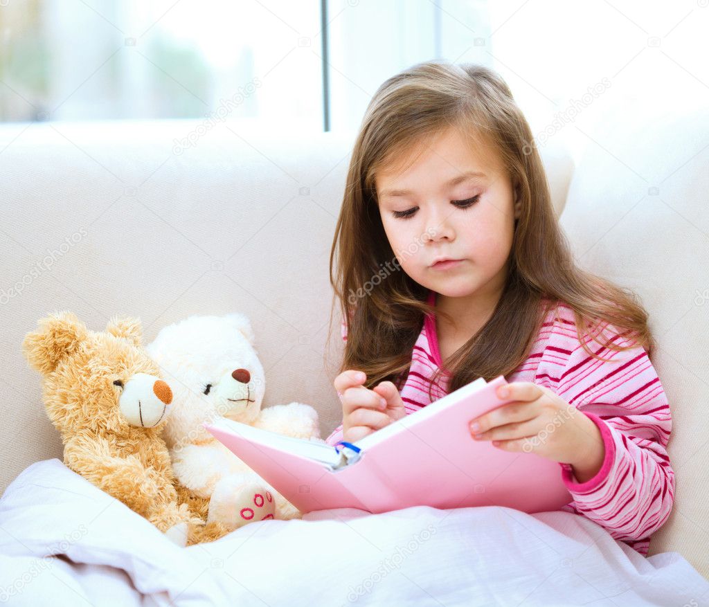 Little girl is reading a story for her teddy bears
