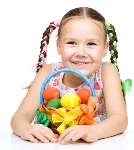 Kleines Mädchen mit Korb voller bunter Eier — Stockfoto