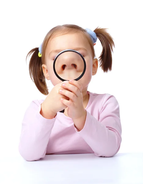 Cute little girl is playing with magnifier — Stock Photo, Image