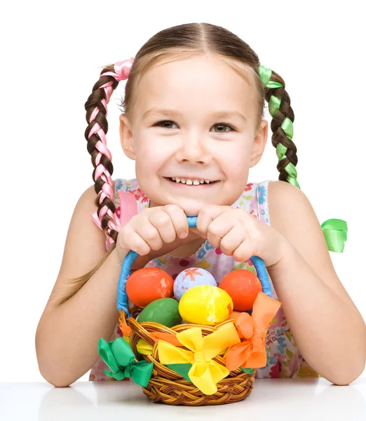 Kleines Mädchen mit Korb voller bunter Eier — Stockfoto