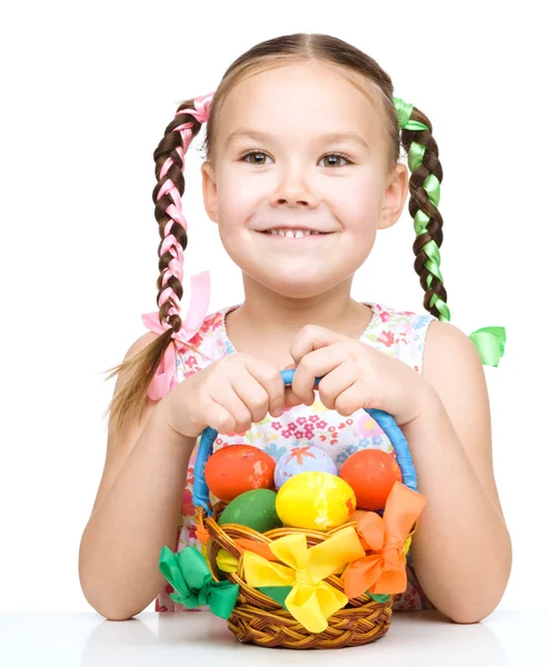 Kleines Mädchen mit Korb voller bunter Eier — Stockfoto