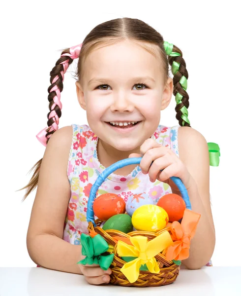 Kleines Mädchen mit Korb voller bunter Eier — Stockfoto