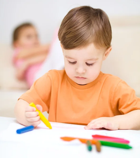 Маленький хлопчик малює на білому папері — стокове фото