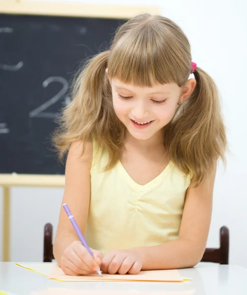 Little girl is writing using a pen — Stock Photo, Image